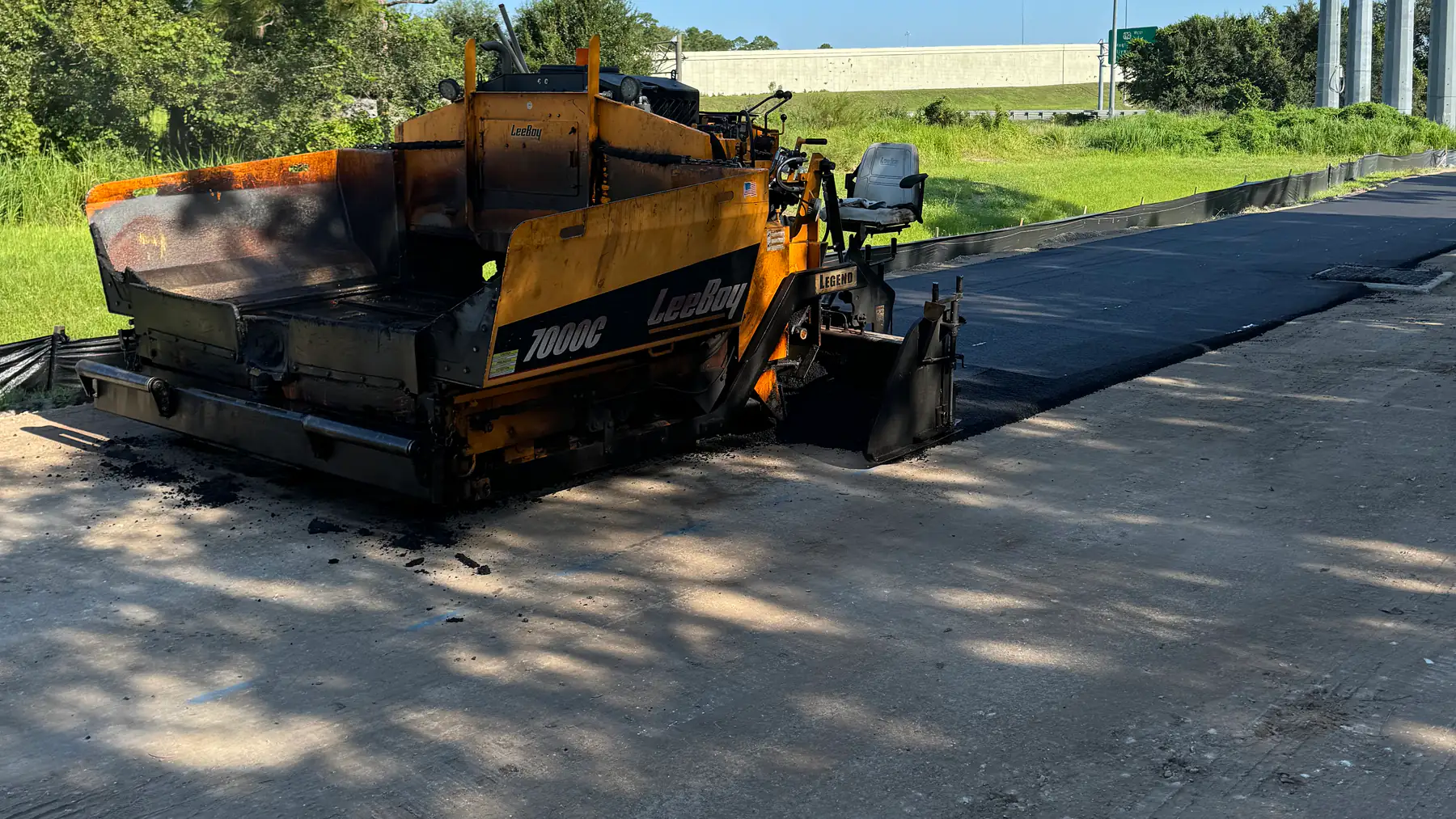 Commercial asphalt paving in Hudson, FL: a LeeBoy paver laying a fresh hot-mix asphalt mat on a commercial roadway